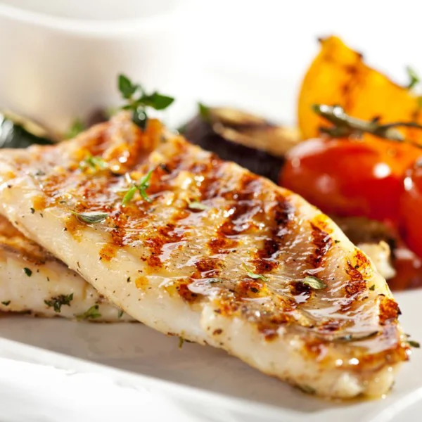 Grilled fish fillet with bbq vegetables and herbs.