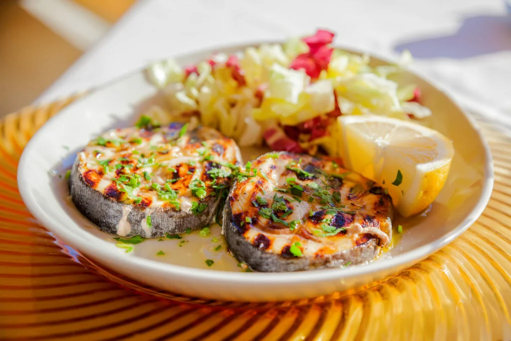 Close up of two grilled swordfish steaks with lemon slice