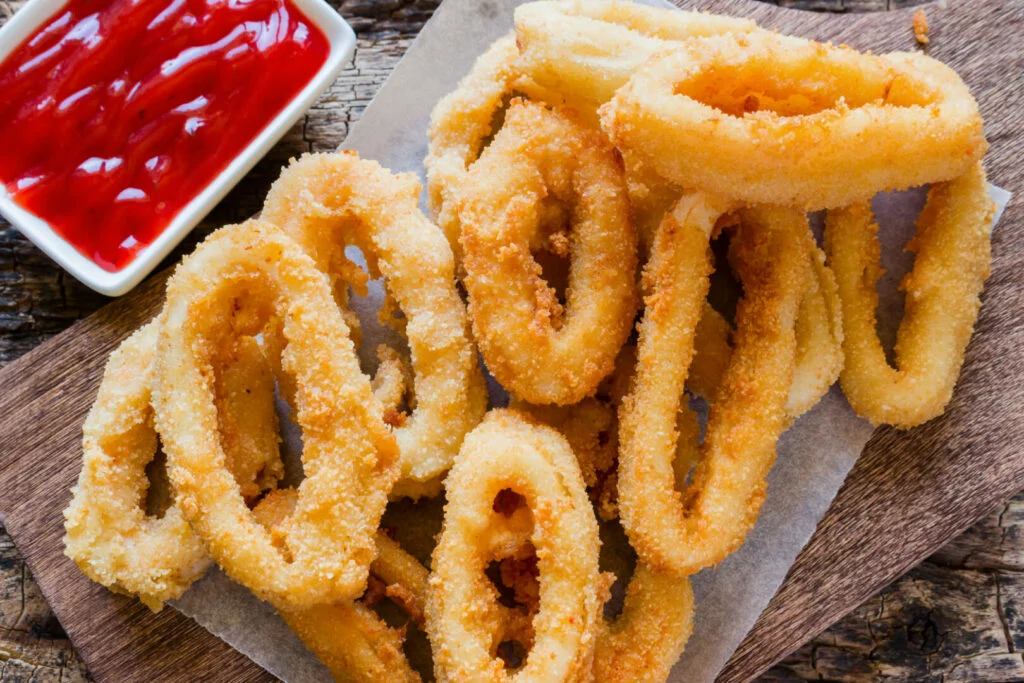 Squid rings breaded with a sauce on a wooden background