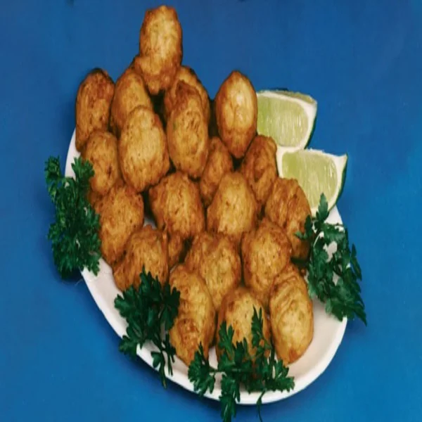 Fried Fritters made of conch meat on a white plate served with lemon and parsley